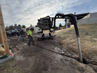  Vacuum truck and technician performing hydro excavation near a hillside residential property 
