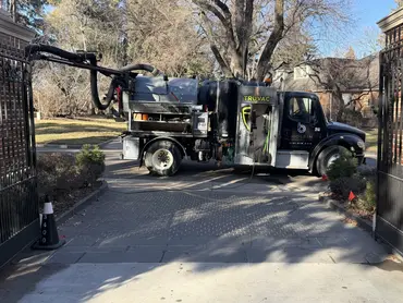  Biolein TruVac hydrovac truck extending vacuum hose through a gated residential driveway in Denver 