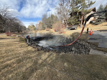  Biolein technician vacuuming built-up sediment from a residential pond with a hydro hose 