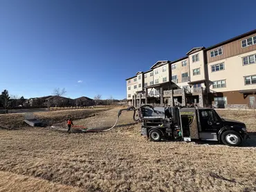  Vacuum truck and technician cleaning a drainage swale near a multi-family apartment complex 