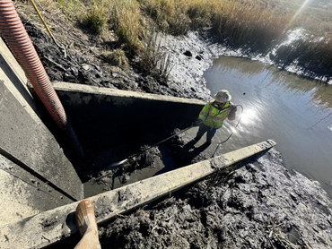  Overhead view of a Biolein technician clearing a concrete drainage culvert with a pressure hose 