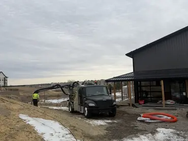  Biolein TruVac truck extending vacuum hose at a commercial building construction site 